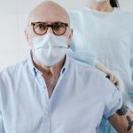 Homem idoso recebe uma dose de vacina de um profissional de saúde em uma unidade de atendimento.