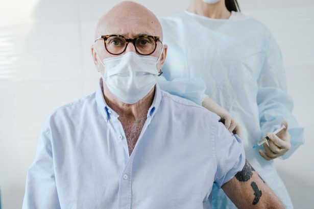 Homem idoso recebe uma dose de vacina de um profissional de saúde em uma unidade de atendimento.