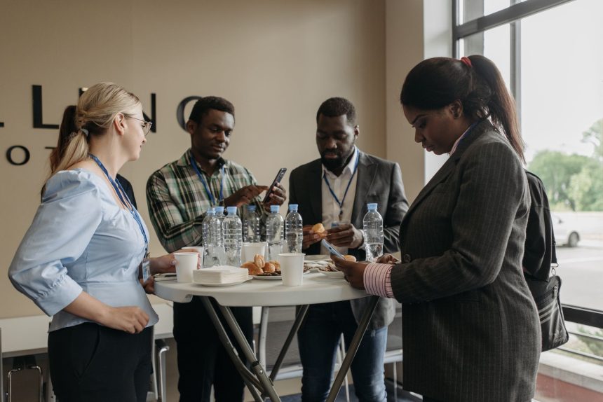 Profissionais conversam e trocam ideias durante um intervalo de evento empresarial em ambiente interno