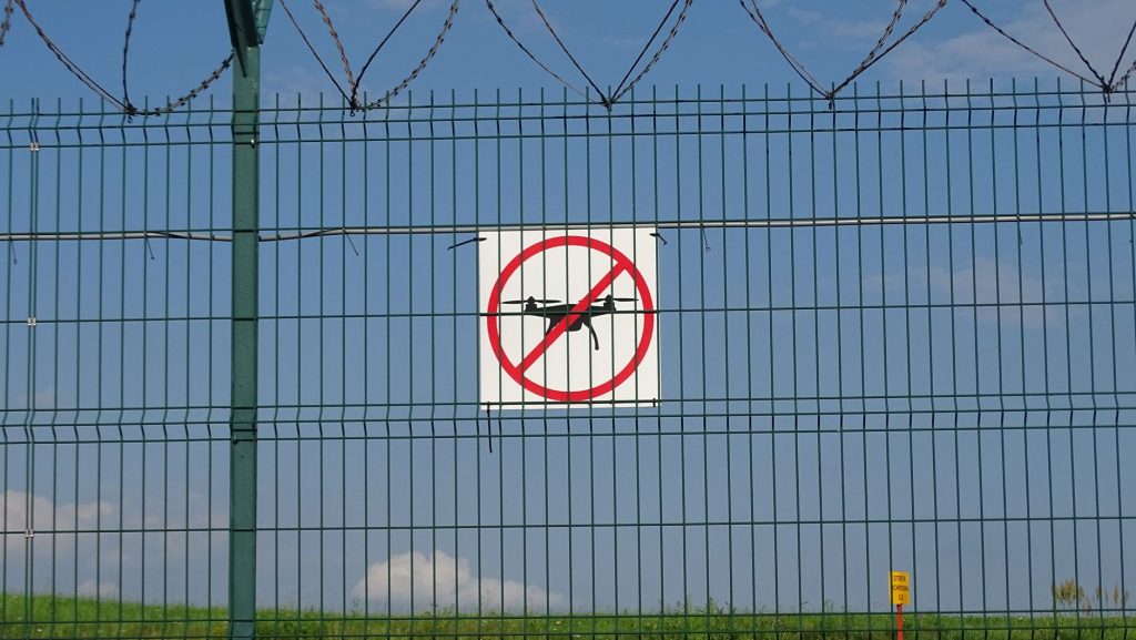 Placa de proibido voar drones afixada em uma cerca de arame farpado.