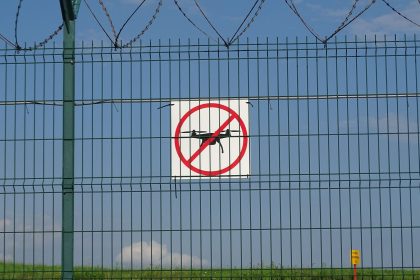 Placa de proibido voar drones afixada em uma cerca de arame farpado.