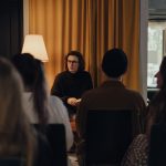 Autor conversa com participantes durante um encontro literário em ambiente interno