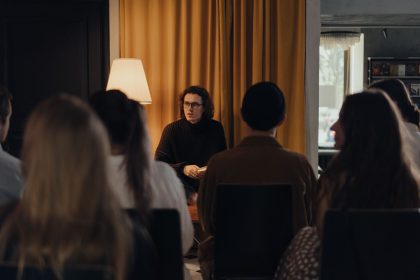 Autor conversa com participantes durante um encontro literário em ambiente interno