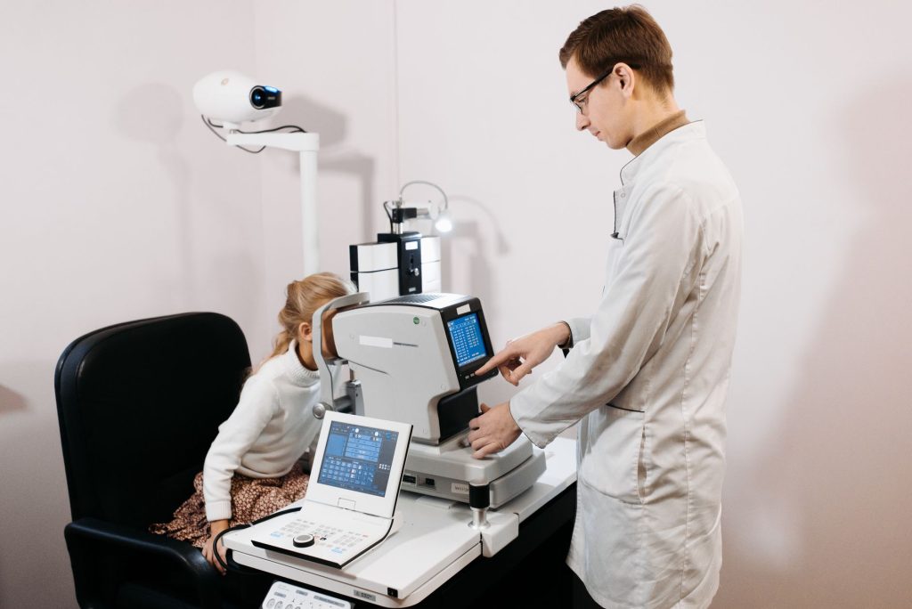 Optometrista examina os olhos de uma criança com equipamento oftalmológico em uma clínica.